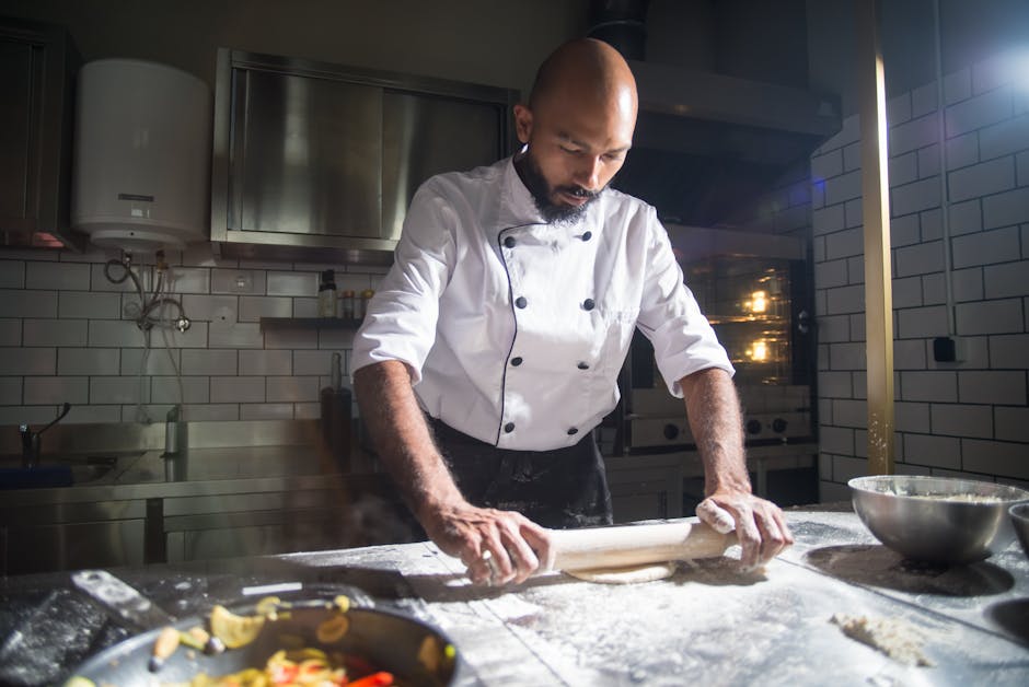 A focused chef expertly rolls dough on a floured kitchen counter, highlighting culinary precision.